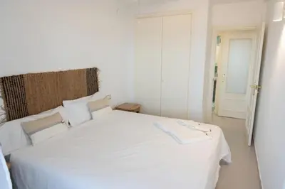 a white bed in a white room with a door at Espacio2,1a línea,jacuzzi,piscina in Cullera