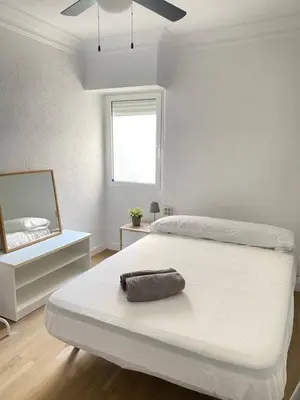 a white bedroom with a large white bed and a mirror at Alojamiento junto Aeropuerto Valencia A in Manises