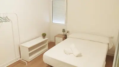 a white bedroom with a bed and a window at Alojamiento junto Aeropuerto Valencia A in Manises