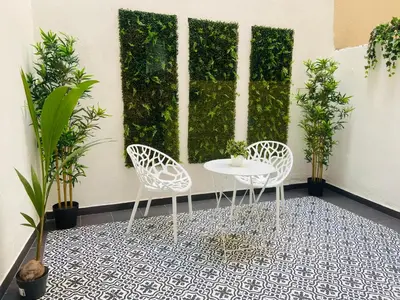 two chairs and a table in front of a wall with plants at Apartamento Ciencias & Maritim in Valencia