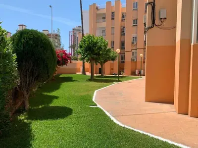 a courtyard with grass and trees and a building at Premium Beach Flat in Las Canteras