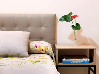 a vase with a flower on a night stand next to a bed at Hostal Antigua Morellana in Valencia