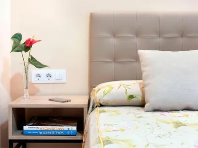 a bed with a vase with a flower on a night stand at Hostal Antigua Morellana in Valencia