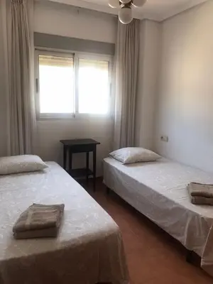 two beds in a room with a window and a table at Aloha frente al Mar in Cullera