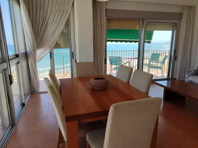a dining room with a table and chairs and a balcony at Aloha frente al Mar in Cullera