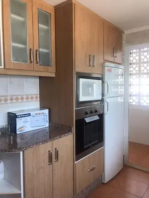 a kitchen with wooden cabinets and a white refrigerator at Aloha frente al Mar in Cullera