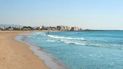 a beach with a person walking in the waves at SERRATELLA Puerto in El Puerto