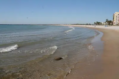 a beach with the ocean and buildings in the background at SERRATELLA Puerto in El Puerto
