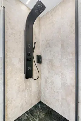 a shower in a bathroom with a wall mounted shower head at City Scape Suites in Valencia