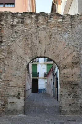 an archway in a stone wall in a street at Alojamientos Segóbriga Rural (Montaña) in Segorbe