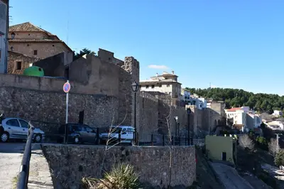 a city with cars parked next to a stone wall at Alojamientos Segóbriga Rural (Montaña) in Segorbe