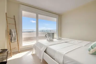 a bedroom with a white bed and a large window at Luxury Penthouse with Panoramic Sea Views in Canet de Berenguer