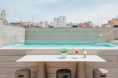 a table and chairs on a balcony with a swimming pool at Vincci Mercat in Valencia