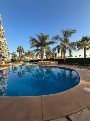 a large swimming pool with palm trees in the background at Apartamento en Moncofa in Moncófar