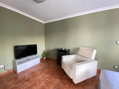 a living room with a white chair and a flat screen tv at Guesthouse in Torrent in Valencia