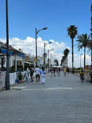 a group of people walking down a street with palm trees at Apartamento playa Veramar patacona in Valencia