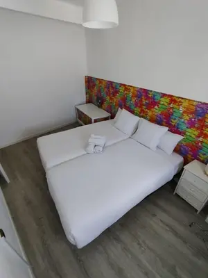 a large white bed in a room with a colorful wall at rural relax Valencia in Villar del Arzobispo