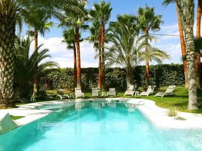 a swimming pool with chairs and palm trees at All Nature Villa-25min from Valencia in Valencia