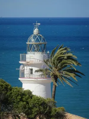 a lighthouse with a palm tree in front of the ocean at NUEVO, a 90 metros de la playa y con vistas al mar in Cullera