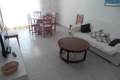 a room with two beds and a table with a night stand at Voramar Serviplaya Solo Familias in Casas Las Basas