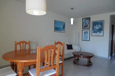 a dining room with a table and chairs and a couch at Voramar Serviplaya Solo Familias in Casas Las Basas