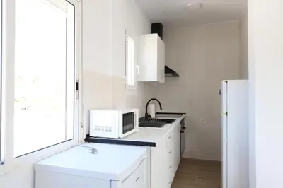 a white kitchen with a sink and a microwave at 2 apartamentos en una excelente villa de playa compartiendo Piscina y Jardín in Sagunto