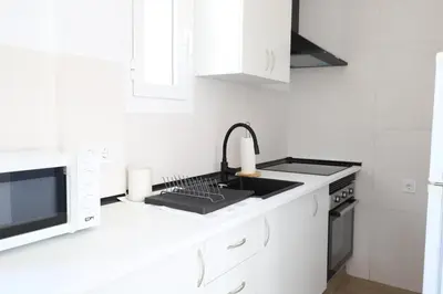 a white kitchen with a sink and a microwave at 2 apartamentos en una excelente villa de playa compartiendo Piscina y Jardín in Sagunto