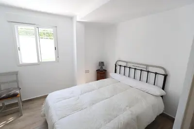 a white bedroom with a large bed and a window at 2 apartamentos en una excelente villa de playa compartiendo Piscina y Jardín in Sagunto