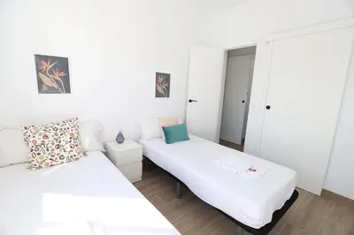 two beds in a room with white walls at 2 apartamentos en una excelente villa de playa compartiendo Piscina y Jardín in Sagunto