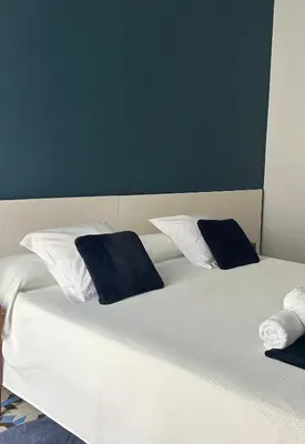 a white bed with two blue pillows on it at L'Esplai Valencia in Valencia