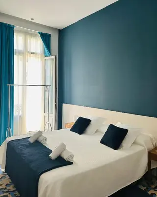 a bedroom with a large white bed with blue walls at L'Esplai Valencia in Valencia