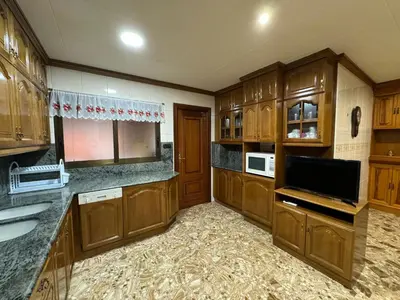 a large kitchen with wooden cabinets and a flat screen tv at Casa Rural Piker in Bolbaite