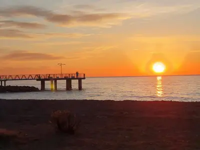 a pier on the water with the sun setting at Chalet Playa Chilches in Chilches
