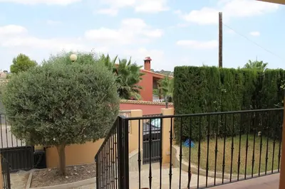 a black fence with a tree in front of a building at La Casa del Olivo en Montserrat - Valencia in Valencia