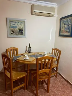 a dining room table and chairs with a bottle of wine at Cosy apartment near the beach in Cullera