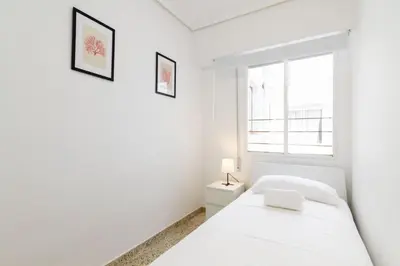 a white bedroom with a bed and a window at GuestReady - El Cabanyal stay near the beach in Valencia