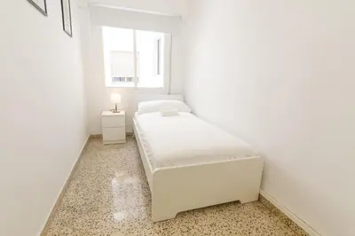 a white bedroom with two beds and a window at GuestReady - El Cabanyal stay near the beach in Valencia