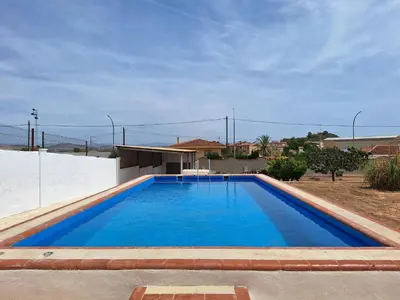 a large blue swimming pool in front of a house at Villa cerca de Valencia con piscina junto a la montaña in Vilamarxant