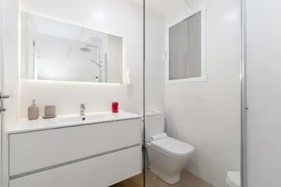 a white bathroom with a toilet and a sink at GuestReady - Lovely flat by Valencia University in Valencia