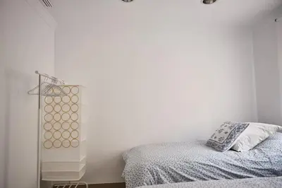 a bedroom with a bed and a white wall at Amplio y cómodo apartamento en el centro in Valencia