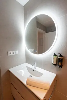 a bathroom with a sink and a round mirror at Dorm4You Arena in Valencia