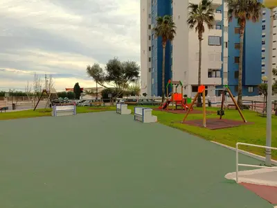 a park with swings and a playground with palm trees at Play-Puig Beach Flat in El Puig