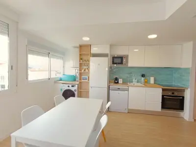 a kitchen with a white table and white cabinets at Play-Puig Beach Flat in El Puig