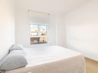 a white bedroom with a bed and a window at Montolivet Gulliver in Valencia
