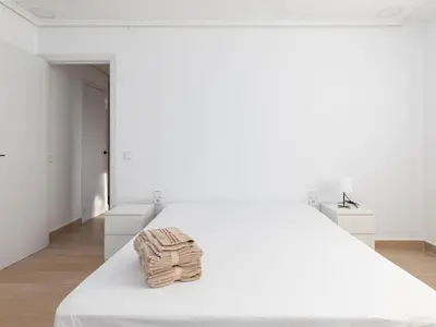 a bedroom with a large white bed with white furniture at Montolivet Gulliver in Valencia