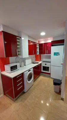 a kitchen with red cabinets and a washing machine at Playa, relax y parking público cerca - Ideal parejas in Cullera