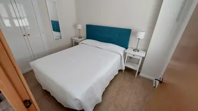 a small bedroom with a white bed and two tables at Playa, relax y parking público cerca - Ideal parejas in Cullera