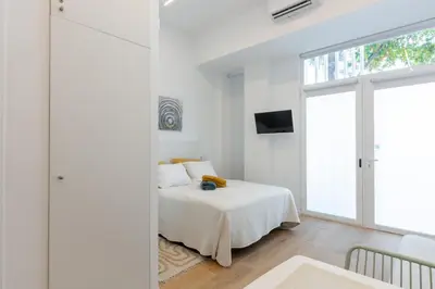 a white bedroom with a bed and a window at Estudio Marina Ivana in Valencia