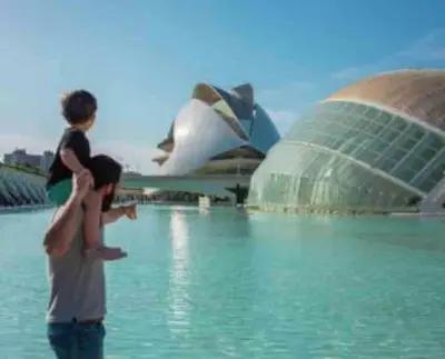 a man holding a child on his shoulders in front of a building at Apto ruzafa patio center science oceanografic in Valencia