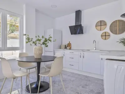 a white kitchen with a black table and chairs at Loft Temporal a 2 min de Playa de Sagunto A1 in Puerto de Sagunto